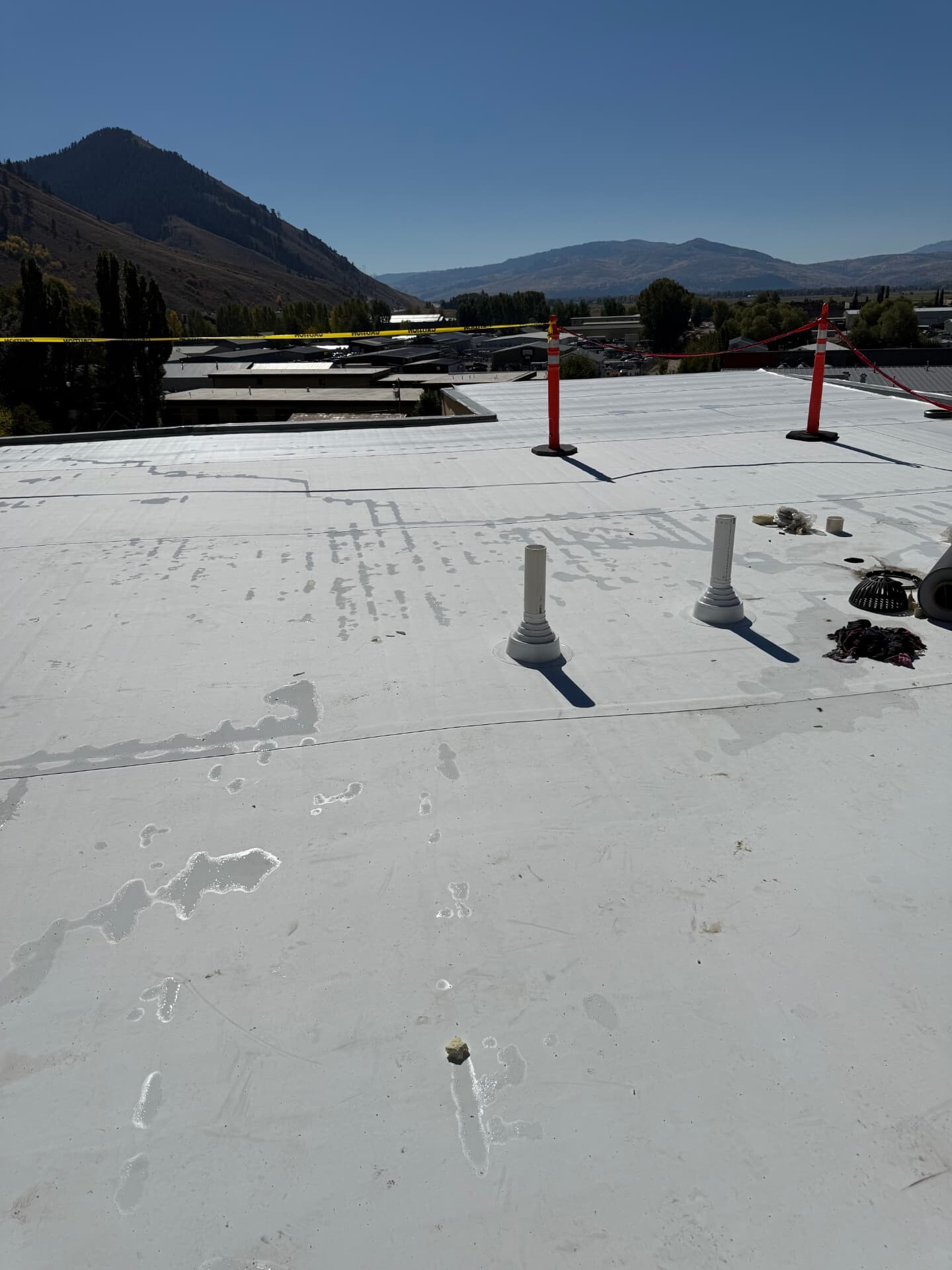 White coated flat commercial roof with vent pipes and mountain views