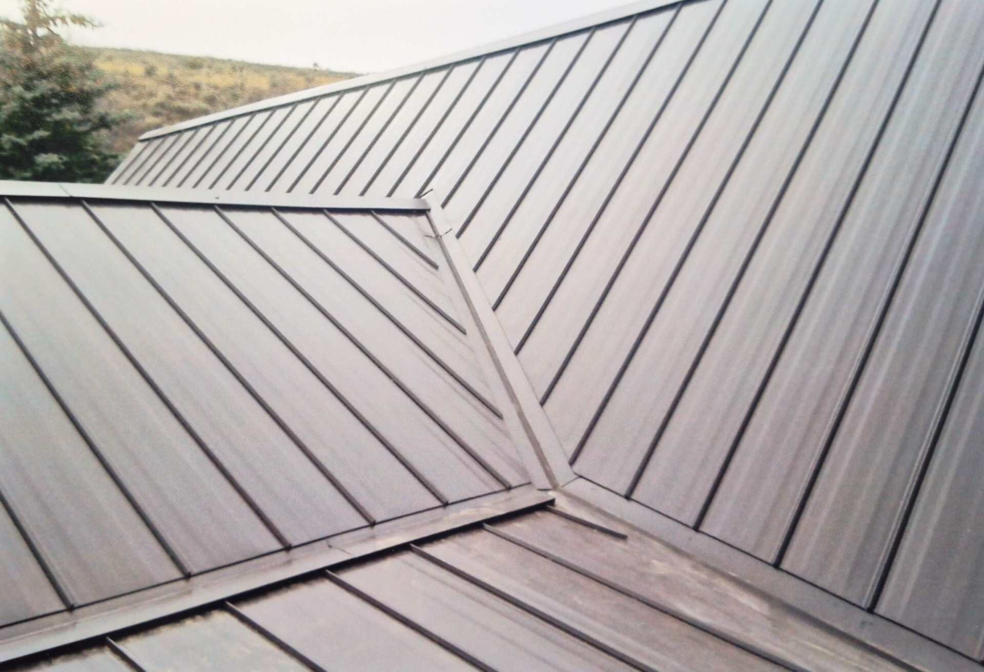 Standing seam metal roof panels meeting at a hip and valley detail