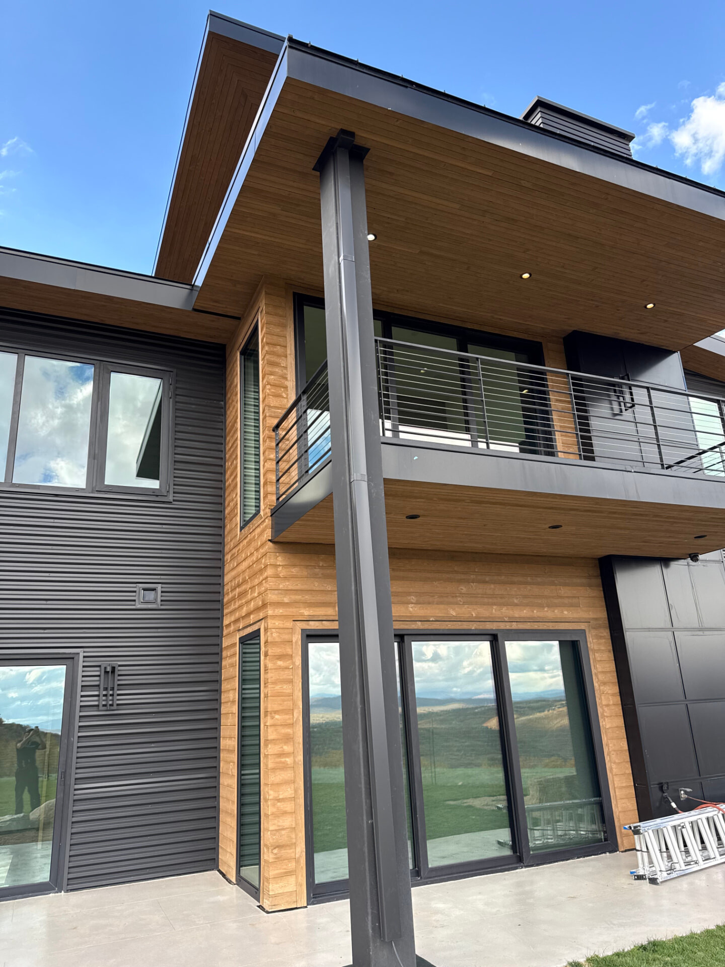 Modern mountain home exterior with wood siding, metal panels and dark downspout