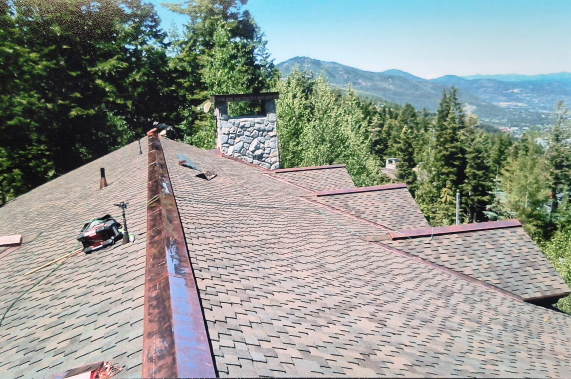 Asphalt shingle roof with copper ridge detail overlooking a mountain valley