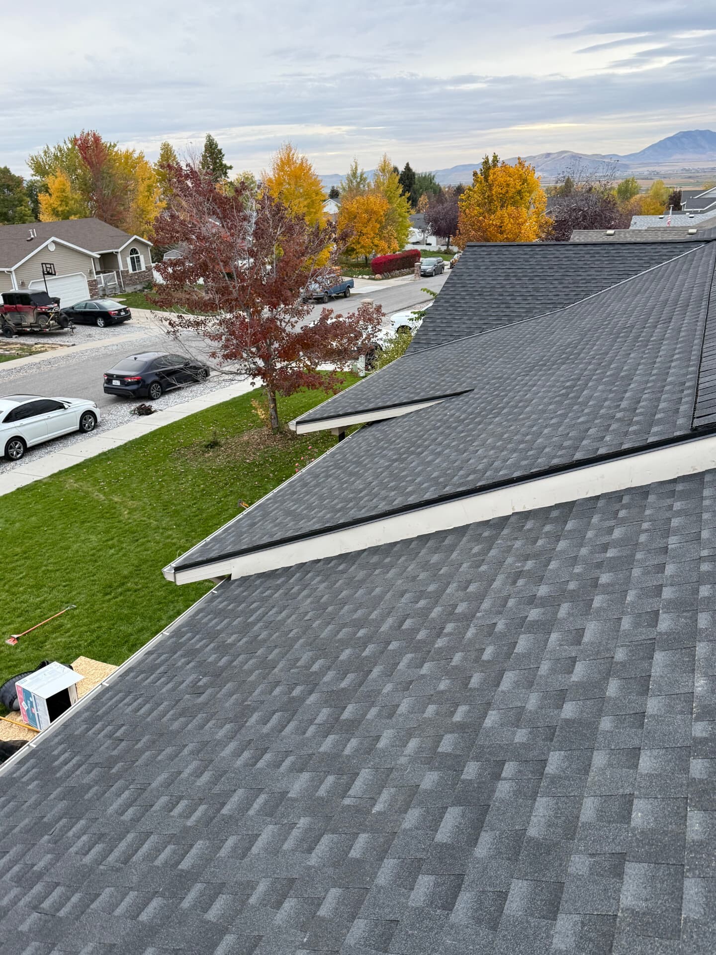 Newly installed dark asphalt shingle roof on a Utah neighborhood home in fall