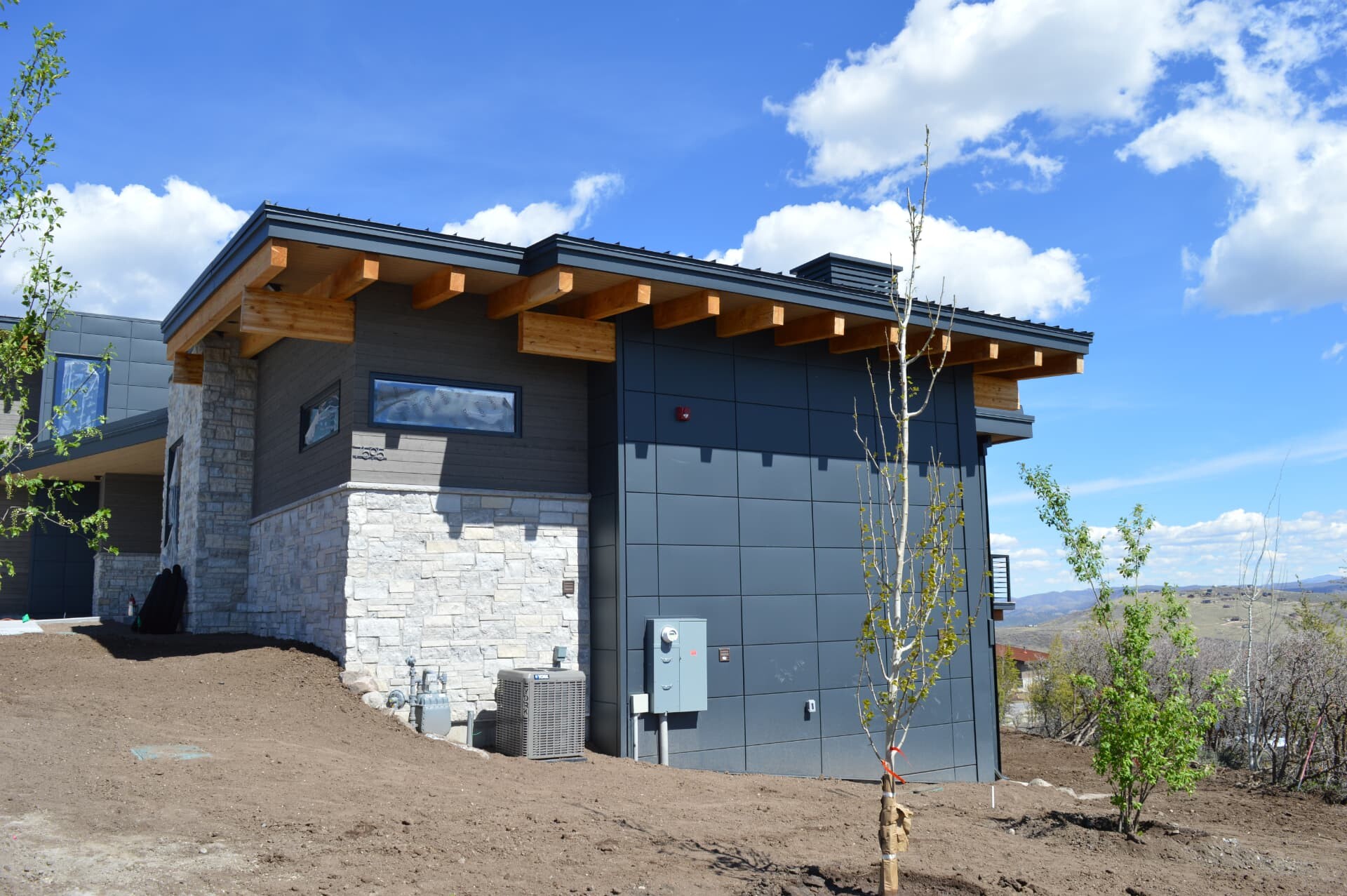 Dark metal wall panels and standing seam roof on a modern mountain home