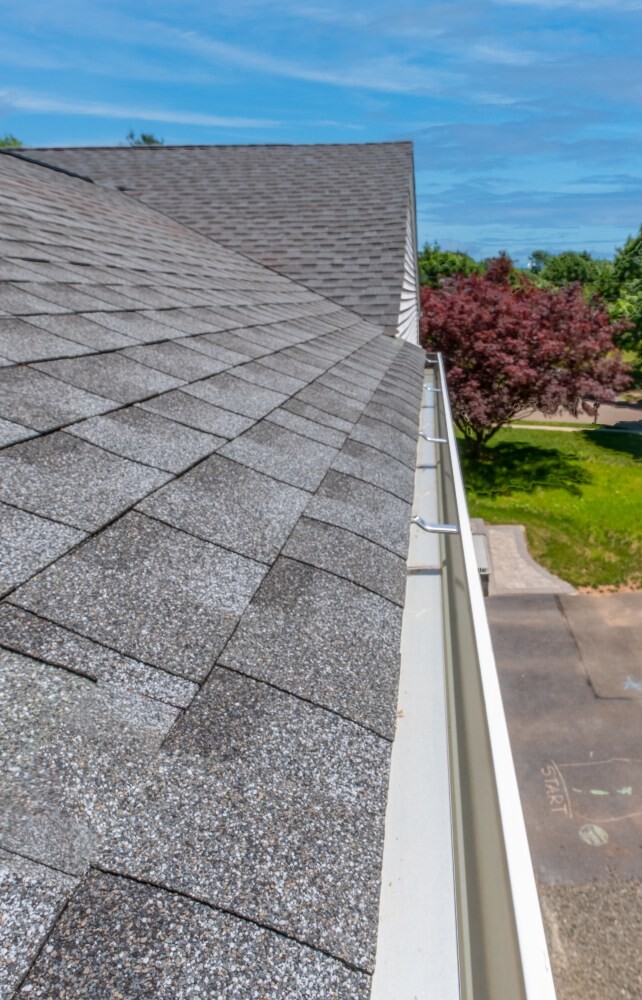 Newly installed gutter along a shingle roof edge