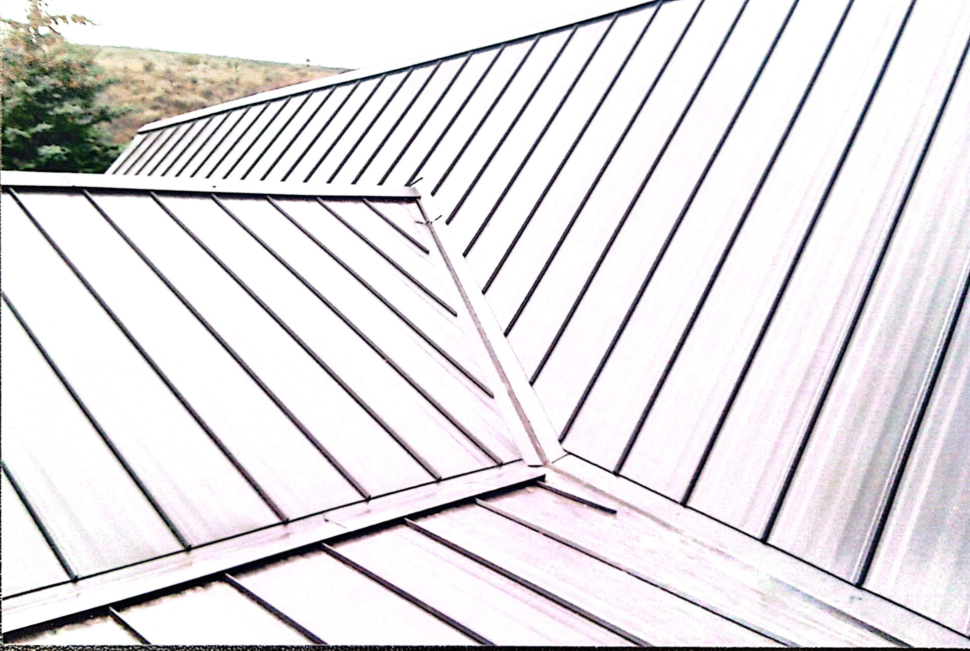 Standing seam metal roof panels meeting at a hip detail