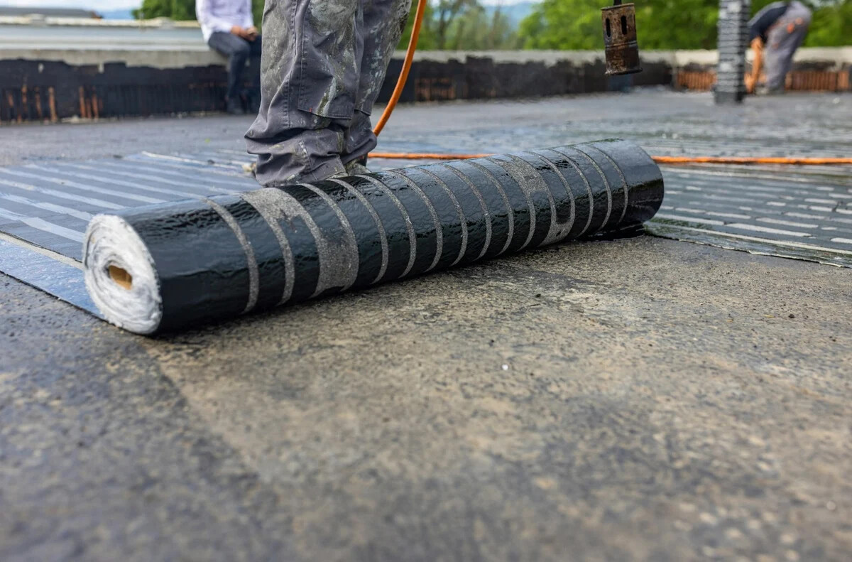 Waterproofing membrane roll being installed on a flat roof surface