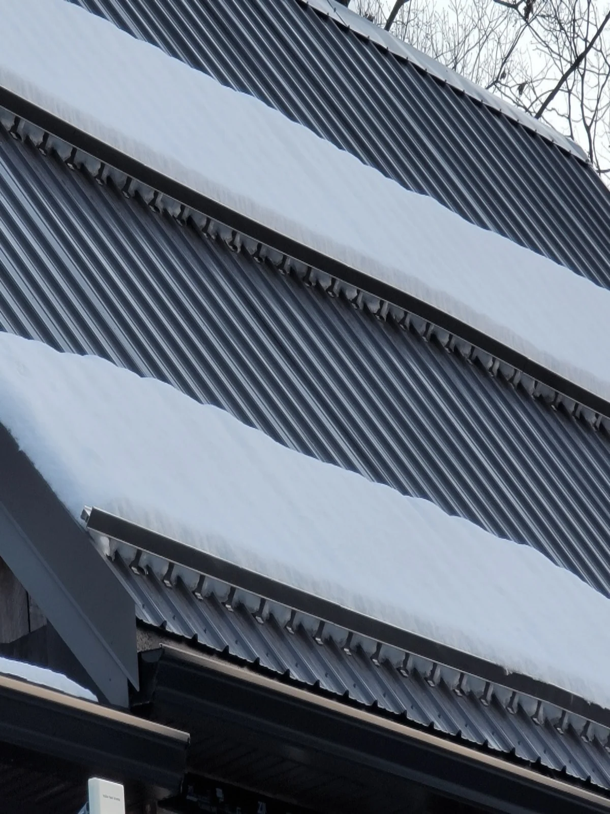 Standing seam metal roof with snow guards and a fresh layer of snow