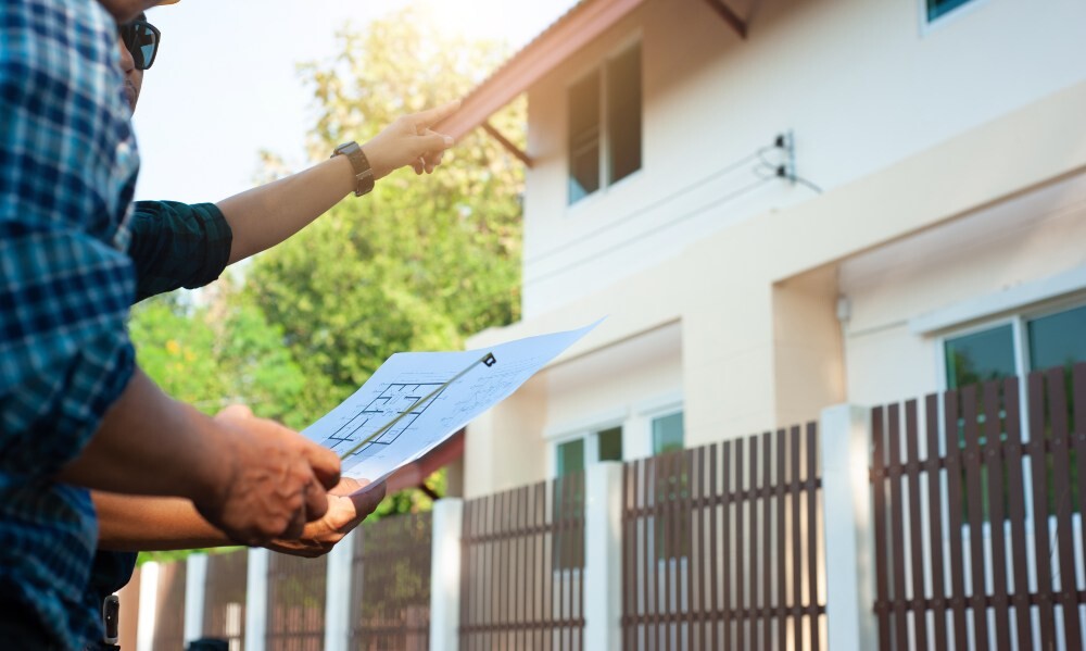 Contractor pointing to the roof edge while reviewing plans with a homeowner